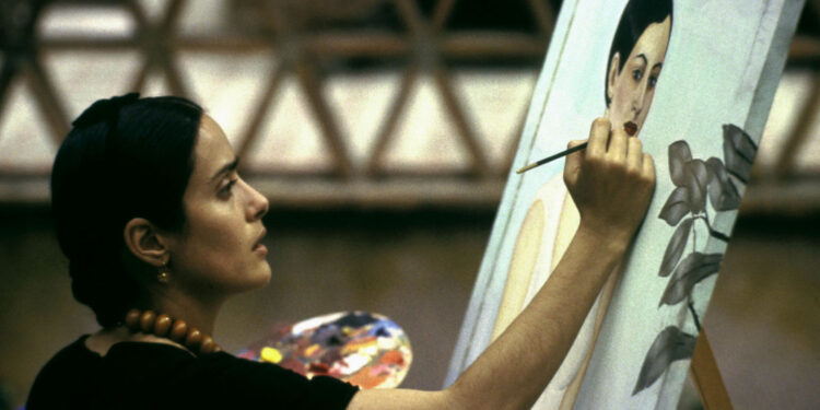 Scena z filmu "Frida" przedstawiająca Salmę Hayek jako Fridę Kahlo, malującą obraz.